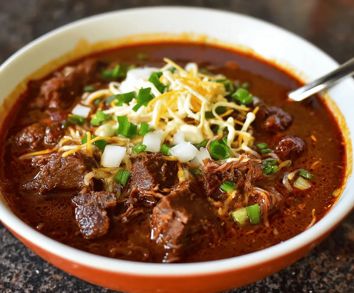 Delicious homemade Texas brisket chili served in a bowl with chopped onions and cilantro, featuring tender brisket, beans, and smoky spices