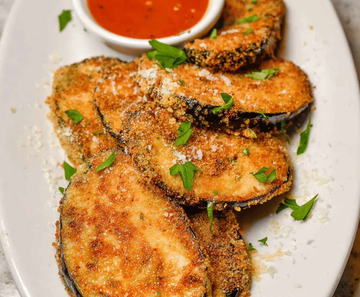 Golden fried eggplant slices with crispy coating, served on a white plate, perfect for a delicious appetizer or side dish.