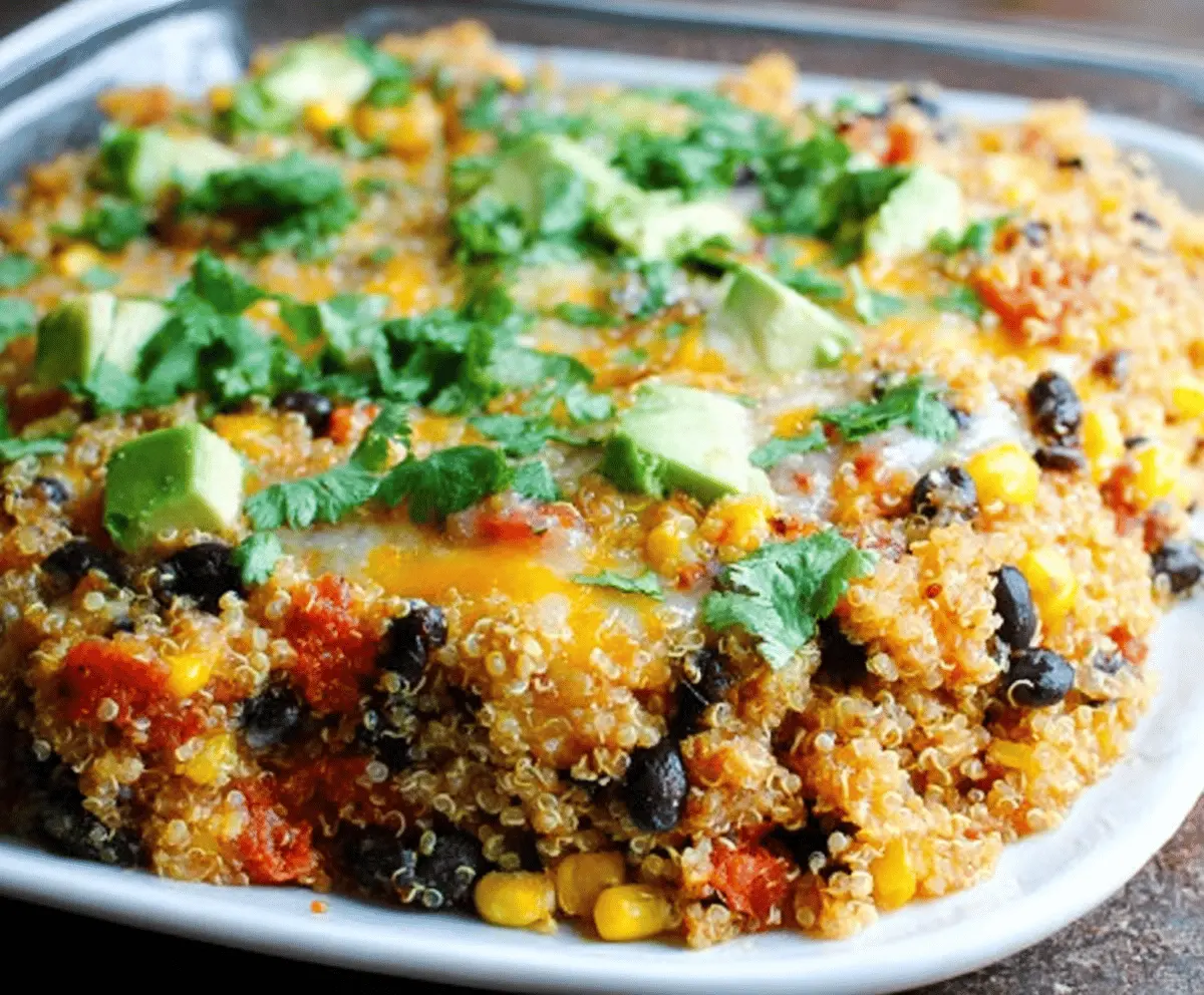 Delicious quinoa and black bean casserole topped with melted cheese, served in a baking dish with fresh cilantro garnish, perfect for a healthy vegetarian meal.