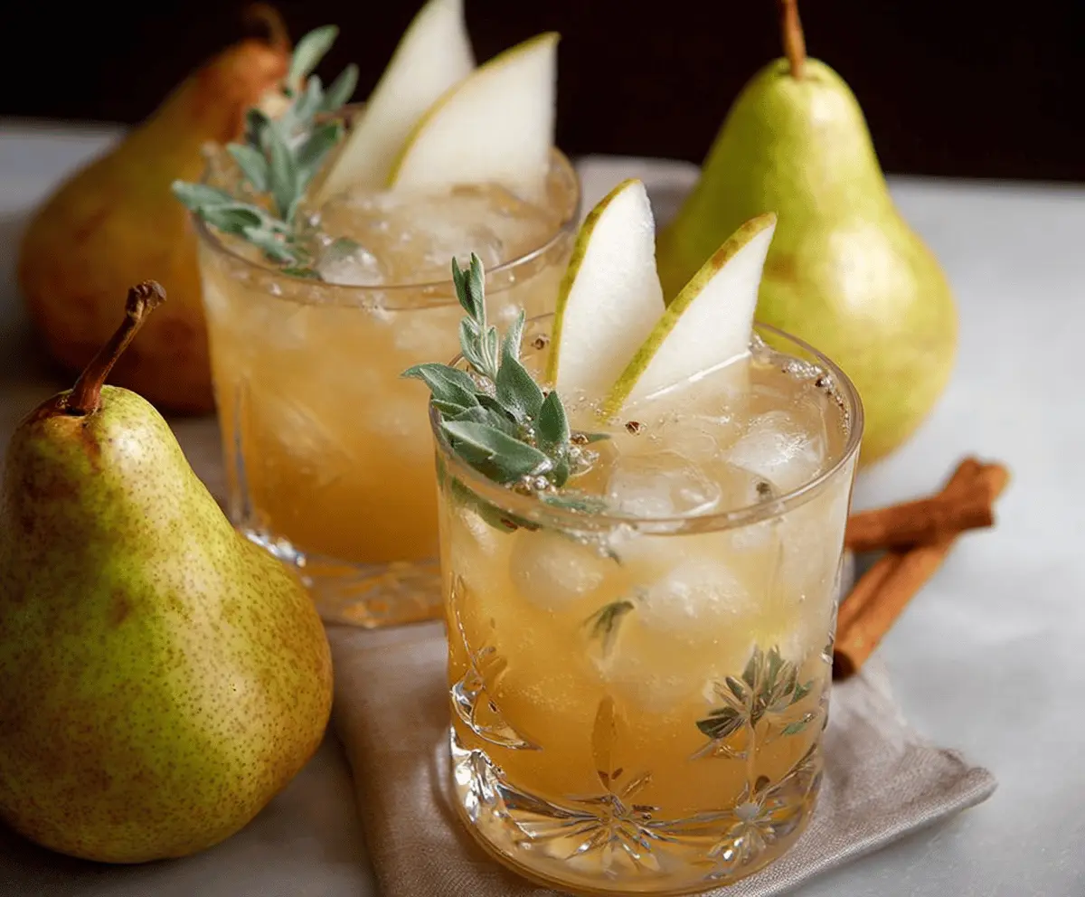 Refreshing Thanksgiving bourbon pear spritzers garnished with fresh pears and mint, perfect for holiday celebrations.