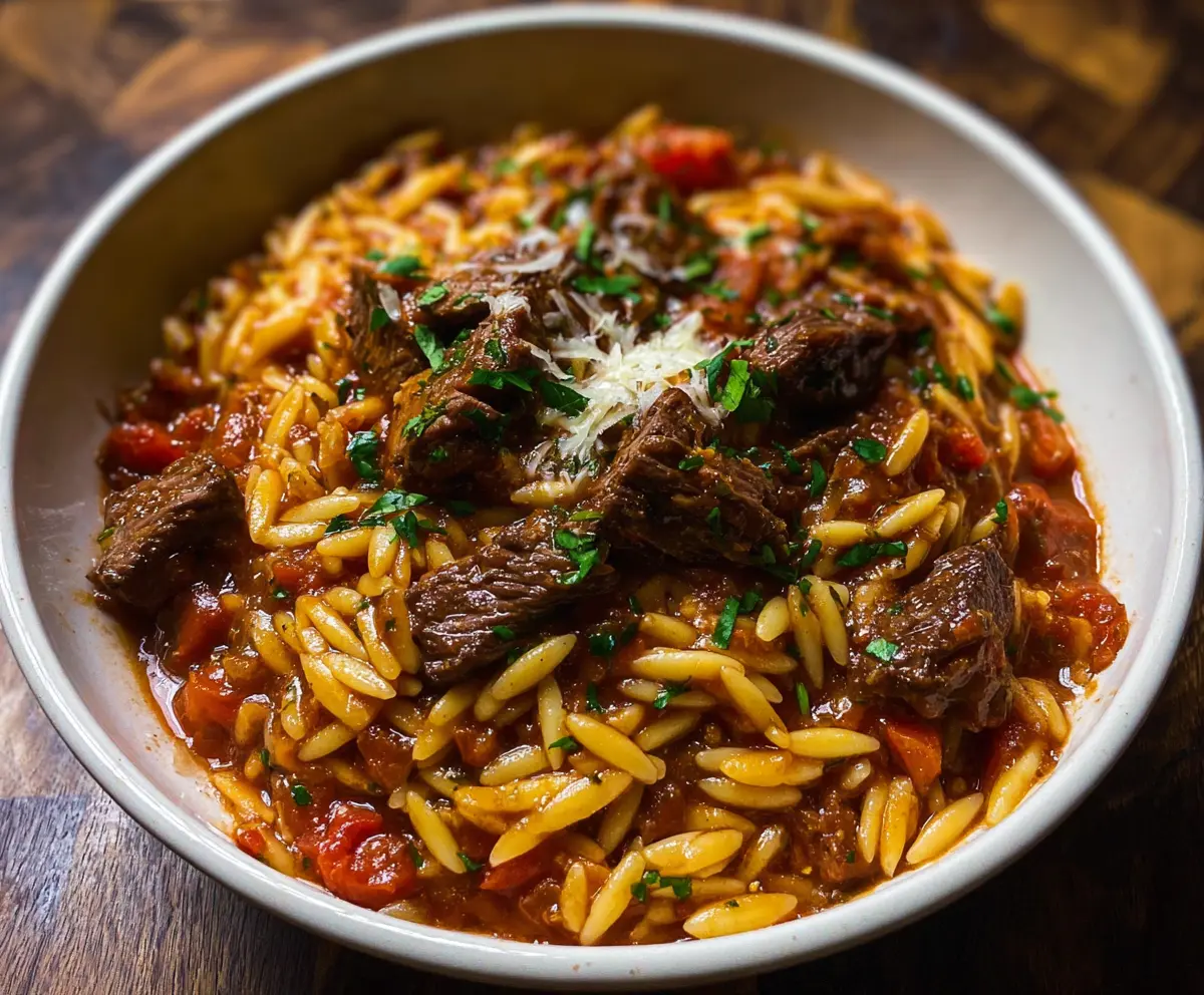 Savory Beef Giouvetsi with tender orzo pasta in a rich tomato sauce, garnished with herbs.