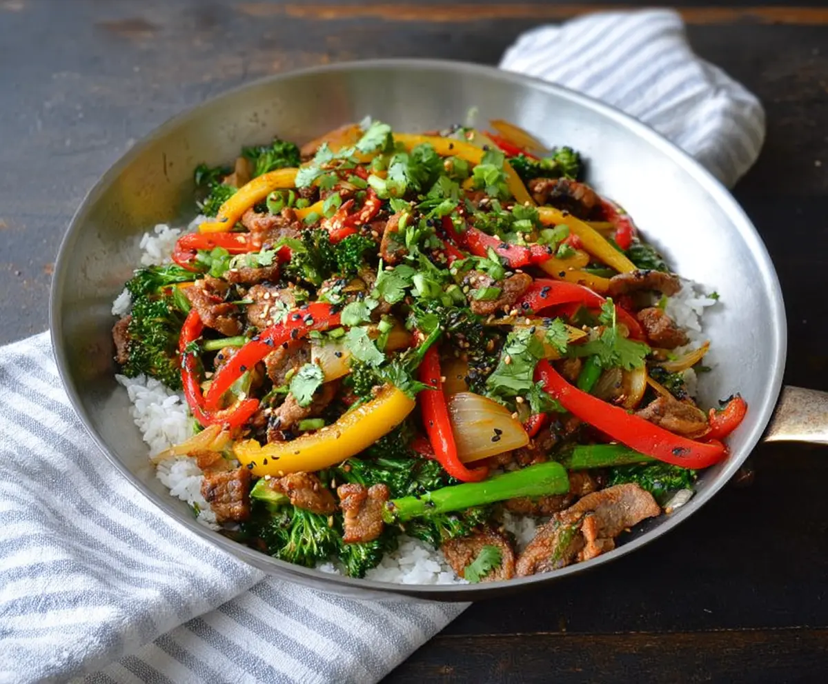 Delicious garlic pork stir fry with colorful vegetables on a white ceramic plate.