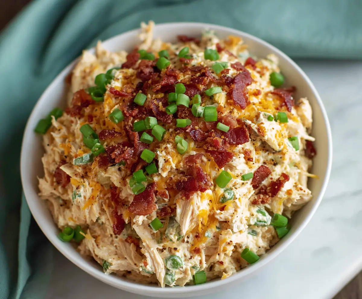 Creamy Jalapeño Popper Chicken Salad with melted cheese and fresh jalapeños on a plate.