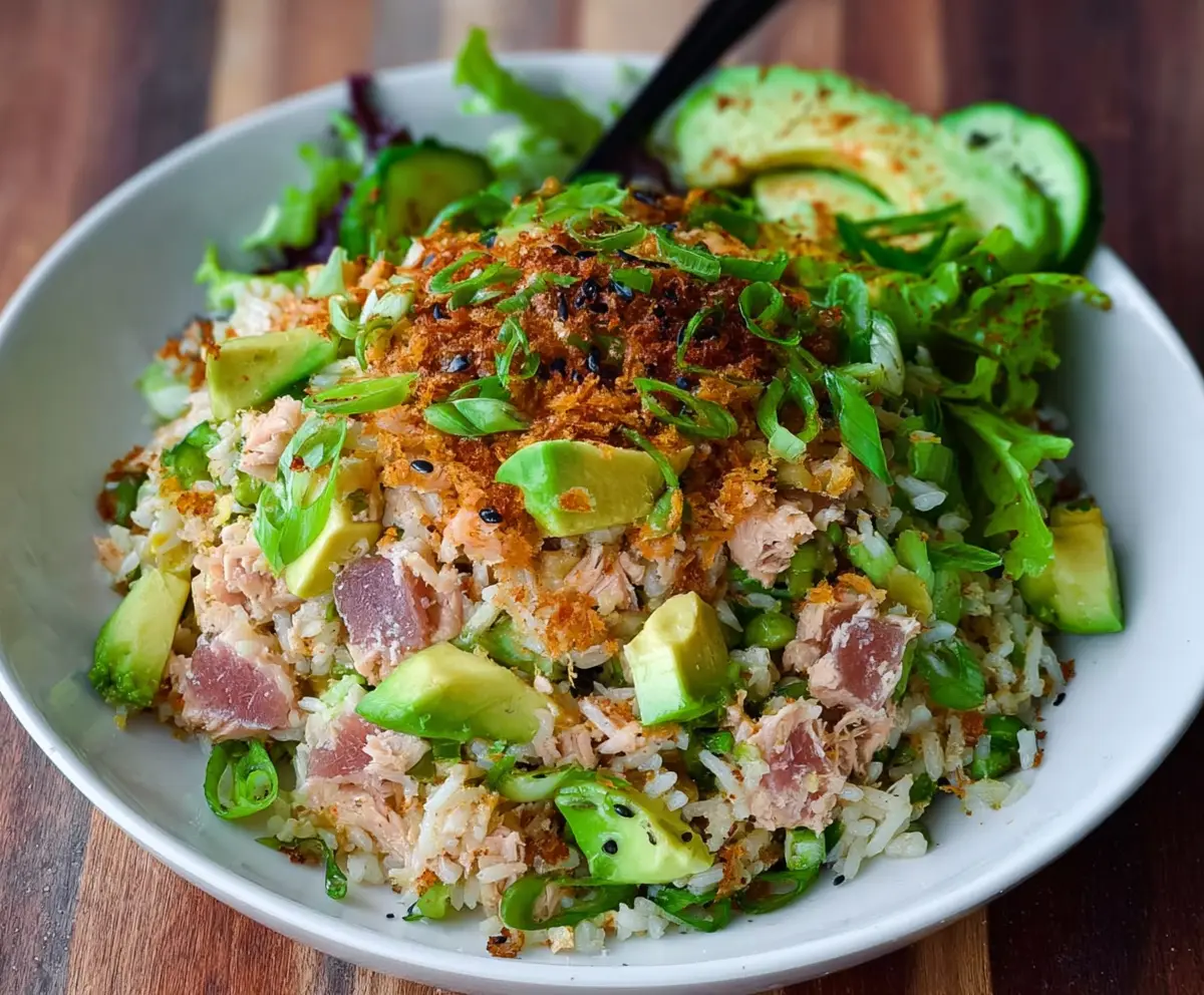 Fresh Tuna and creamy avocado atop crispy rice salad, garnished with herbs for a healthy, flavorful dish.