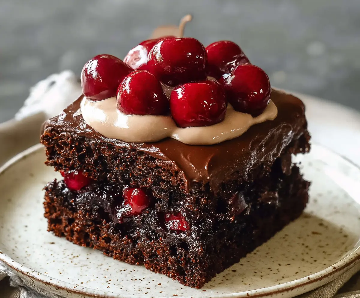 Delicious homemade chocolate cherry cake with rich frosting and fresh cherries on top.