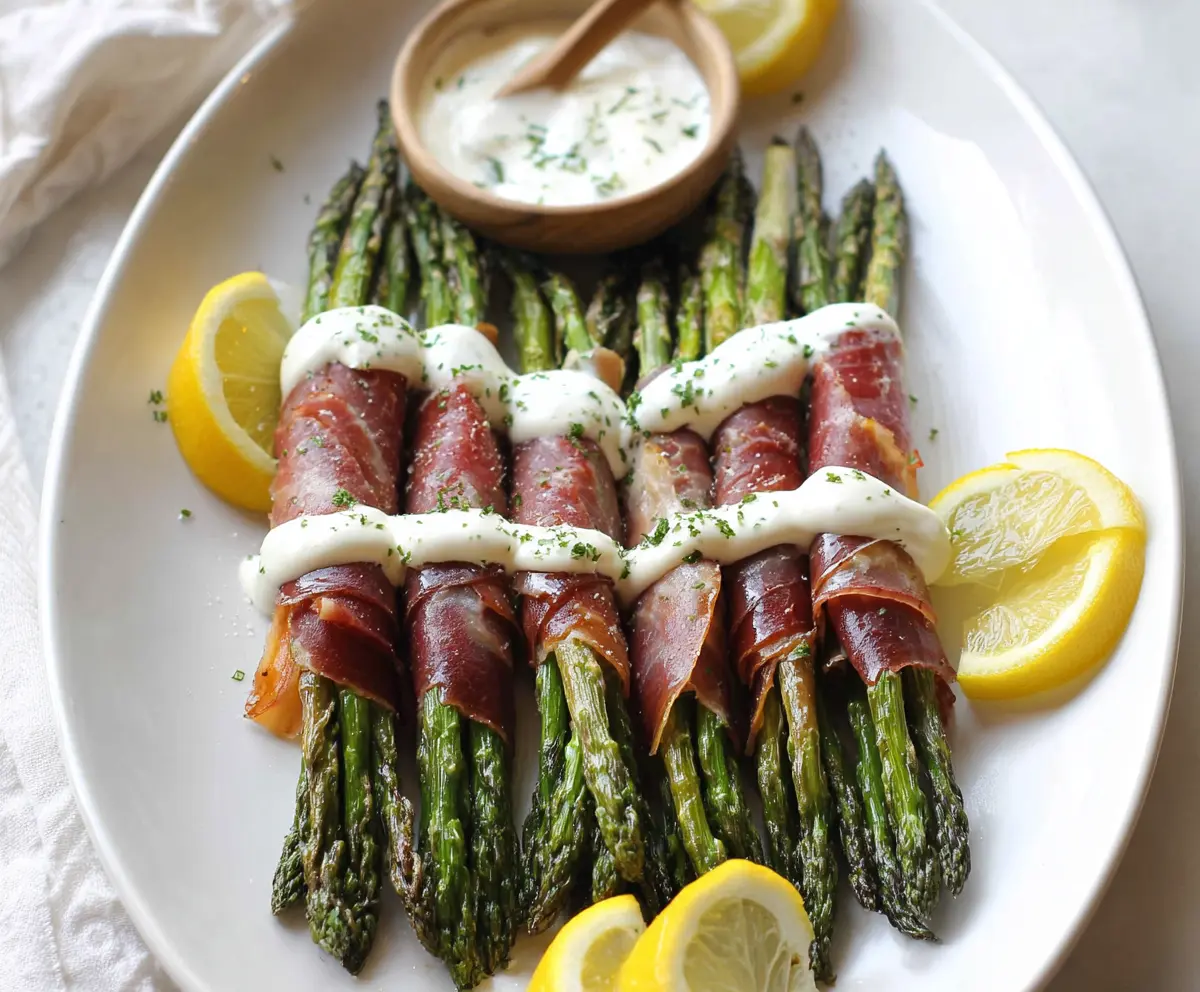 Prosciutto-wrapped asparagus spears served with a tangy lemon cream sauce on a stylish platter.